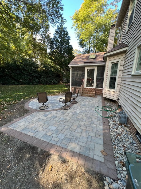 Paver patio seating area beside a home with clean hardscape installation and border gravel